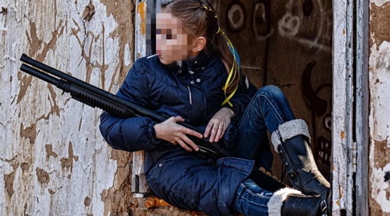 Guerra in Ucraina, la foto simbolo della resistenza di Kiev: una bimba di 9 anni con lecca lecca e il fucile